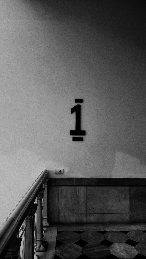 Black and white photo of a stairwell with number 1 emphasized on the wall.